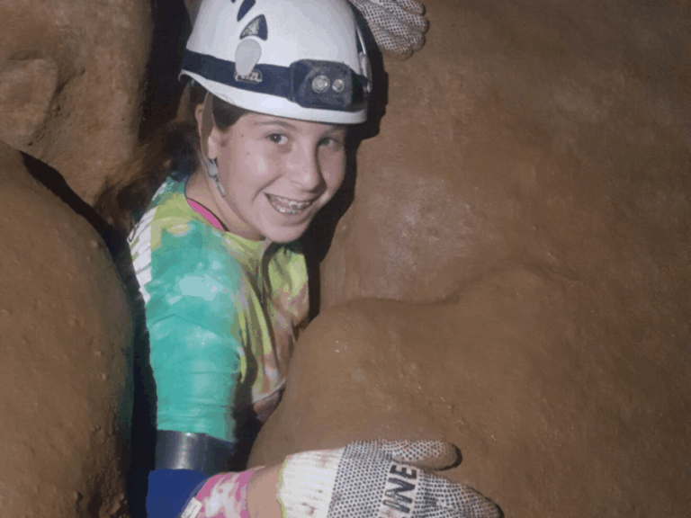 Girl emerging from rock crevice